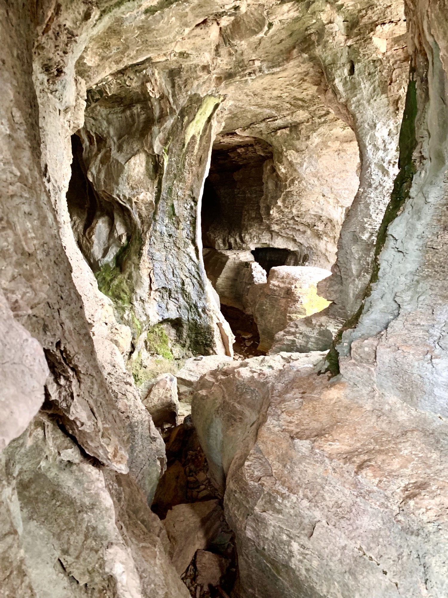 Mouth of a limestone cave with warm light spilling in from outside and pale stone walls inside.